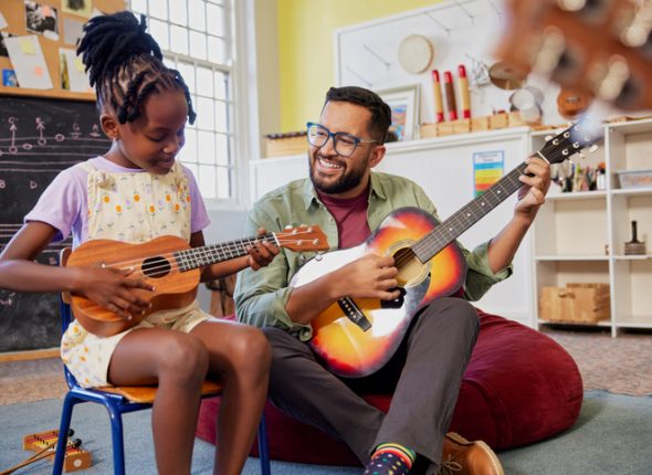 Teacher and students playing guitar together during music lesson